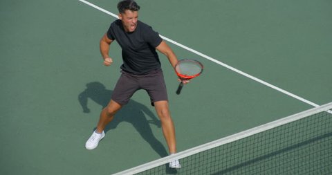 A male Tennis Player plays the winning shot and celebrates.