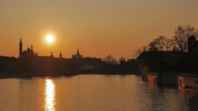 Timelapse of setting sun on the background of the panorama of the city of Wroclaw. Orange sky on the background of the river and the washing vessel. In the distance, darkened buildings.