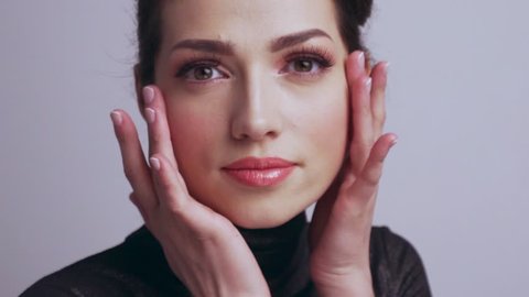 Beautiful woman touches skin of face. Caucasian adult girl cares of skin face.  Beautiful brunette woman.  Slow motion footage.  Beauty treatment. Young woman touches  her healthy  face.    