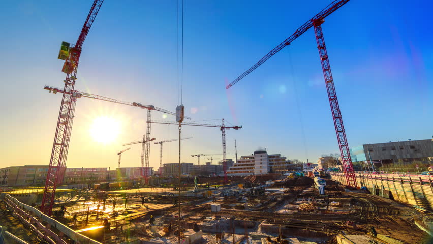 Timelapse footage of a large construction site with several busy cranes at dusk, with clear blue sky and the setting sun | Shutterstock HD Video #1024520093