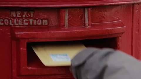 Stanley, Falkland Islands - May 2021: Hand of a Young Man sending Mail, Posting a Letter Into a Post Box, UK. Close Up.