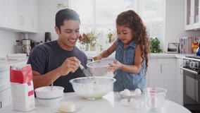 Hispanic father and his young daughter preparing cake mix in their kitchen, close up - Powered by Shutterstock - Get 15% off with code: PIKWIZARD15