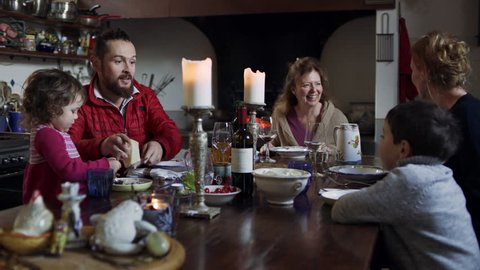 Family prepares to enjoy a meal together in their home at the dinner table by the kitchen. Wide shot on 8k helium RED camera.