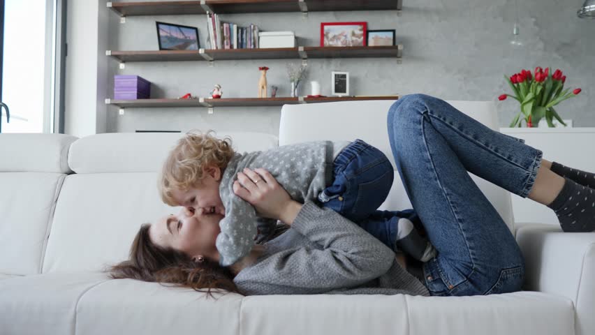 Fun and diversion young mother and little child son at home falling on the couch | Shutterstock HD Video #1024546238