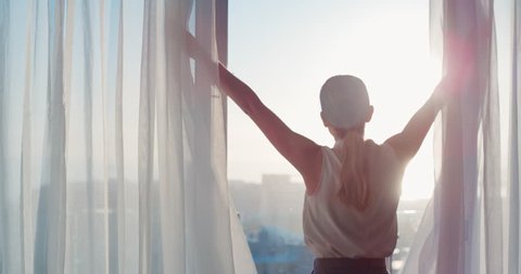 business woman opening curtains in hotel room looking out window at fresh new day successful independent female planning ahead at sunrise