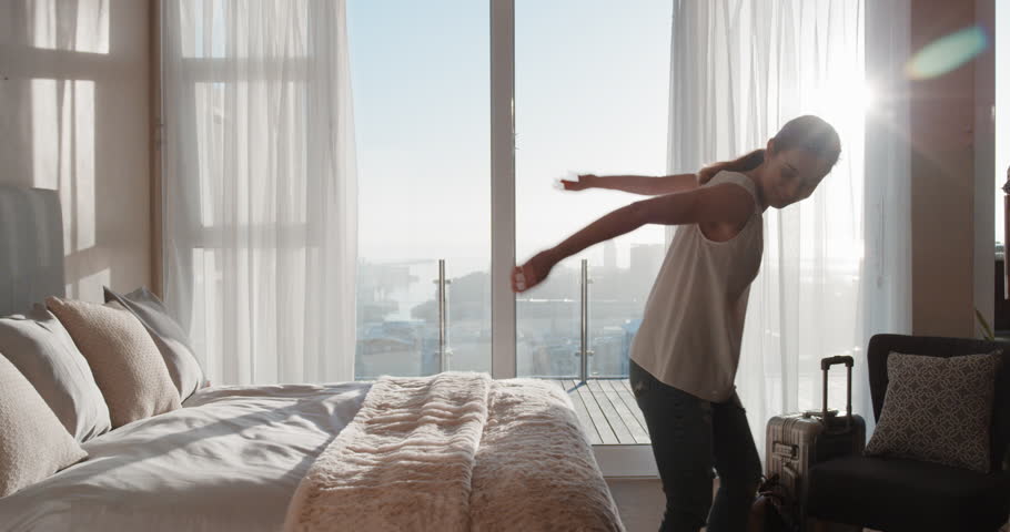 happy young woman jumping on bed resting after successful travel journey enjoying independent lifestyle freedom in hotel room Royalty-Free Stock Footage #1024548095