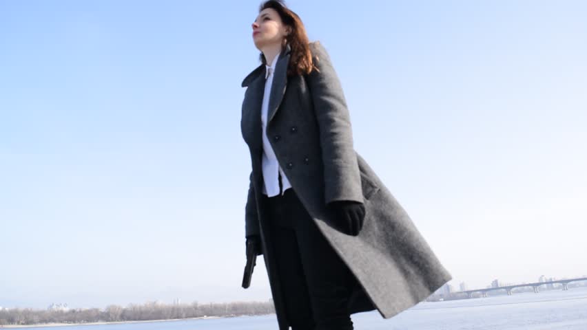Young brunette woman shoots with a gun over a river in the city
