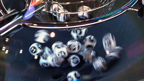 Black and white lottery balls in a rotating bingo machine. Lottery balls in a sphere in motion. Gambling machine and euqipment. Blurred lottery balls in a lotto machine. 4k