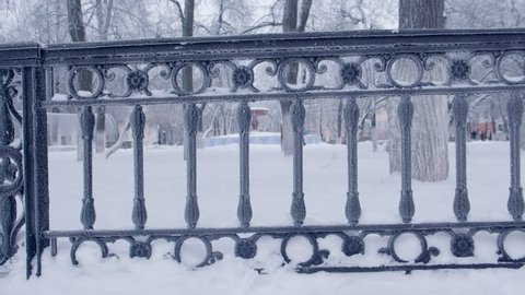 Snow-covered metal railing in the city Park.