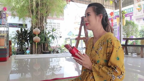 Woman predicting fortune by shaking Chi-Chi Stick, Seam-si, Chinese Way for horoscope in Temple, Thailand.