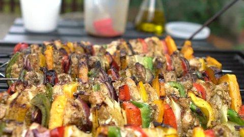 Slow Motion of chef cooking barbecue with skewers on grilled meat. Very delicious brochette on a barbecue in backyard. Food cooked with grilling BBQ in the garden of a house-Dan