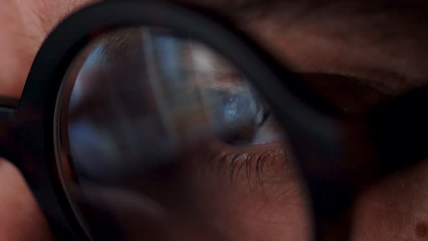 Man in glasses looking on the monitor and surfing Internet. The monitor screen is reflected in the glasses | Shutterstock HD Video #1024578164