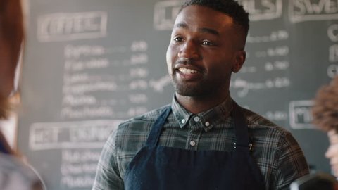 young african american barista man serving customers in cafe using smart watch making contactless payment buying coffee spending money enjoying service