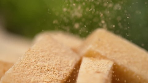 SLOW MOTION, MACRO, DOF: Delicious parmesan cheese is sprinkled over the whole squares. Mouth-watering shot of parmesan cheese being grated over the cubes. Tasty cheese flakes come falling down.
