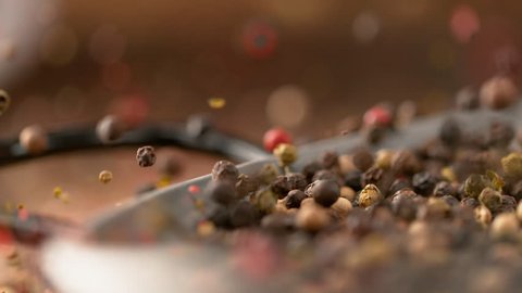 SLOW MOTION, MACRO, DOF: Organic homegrown peppercorns bounce out of the frying pan that falls onto the table. Flavorful and aromatic pepper seeds come falling down onto a kitchen counter in metal pan