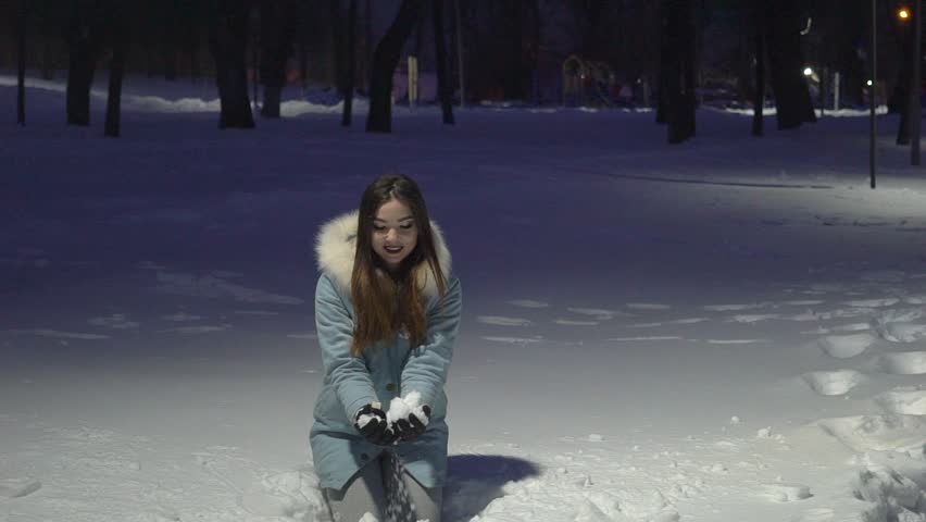 Young Woman Throwing Snow In The Air In Winter Forest