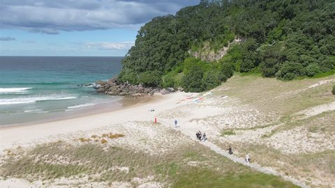 Aerial: People walking down a pathway on tropical Sandy beach on a sunny day. Onemana, Coromandel Peninsula, New Zealand. 18 October 2018 