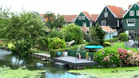 Typical colorful Dutch houses at Marken island with small pond in the foreground. Marken, North Holland, Netherlands. 4K