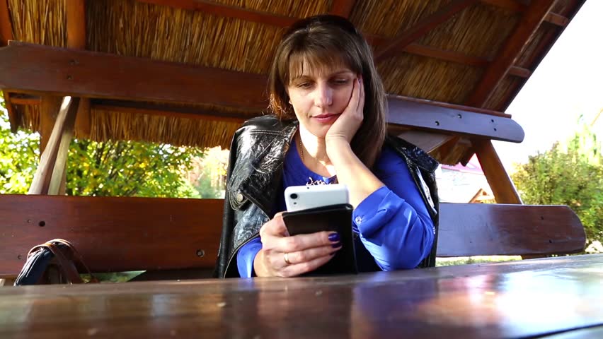The girl in the gazebo looks into a mobile phone