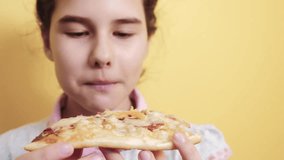 happy little girl eating a slice of pizza concept. lifestyle teenager child hungry eats a slice of pizza. slow motion video. pizza fast food concept