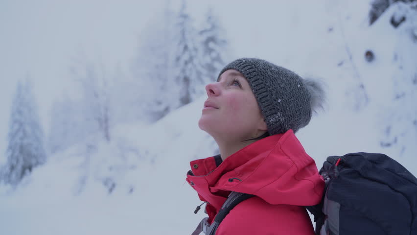 young caucasian woman hiking in woods covered with snow. Looking back