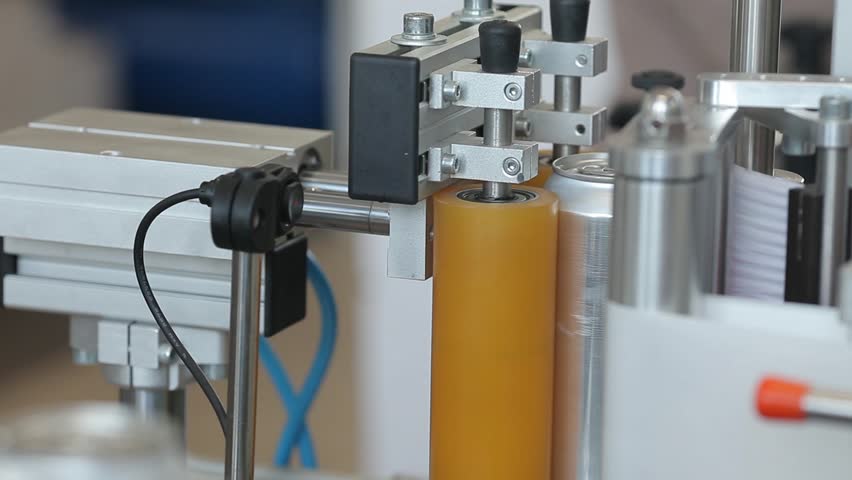 Conveyor for filling aluminum cans. Banks move along the conveyor and the machine sticks labels on them