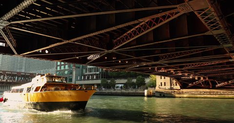 Chicago, Illinois, USA - September 22, 2018: People walk along the Riverwalk tral as boats, ferries and water taxi's float along the Chicago River under the Dearborn Street Bridge in Chicago Illinois 