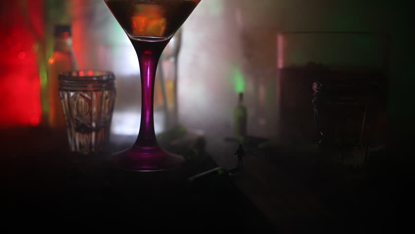 Abstract alcoholism concept. Silhouette of a man standing in the middle of the road on a misty night with giant glasses filled with alcoholic beverage. Creative artwork decoration