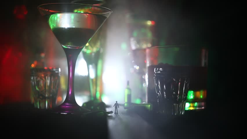 Abstract alcoholism concept. Silhouette of a man standing in the middle of the road on a misty night with giant glasses filled with alcoholic beverage. Creative artwork decoration