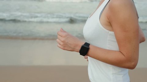 sport female runner run wearing smartwatch with watchband blank black glass bent touchscreen on natural sea ocean beach background