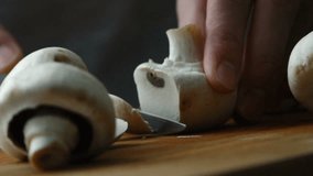 Shot of woman chef cutting mushrooms on chopping wooden board. Slow motion video