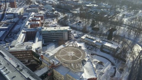Aerial view by drone moving up from a helipad in the middle of the city of Orebro under the snow during a sunny day, Sweden