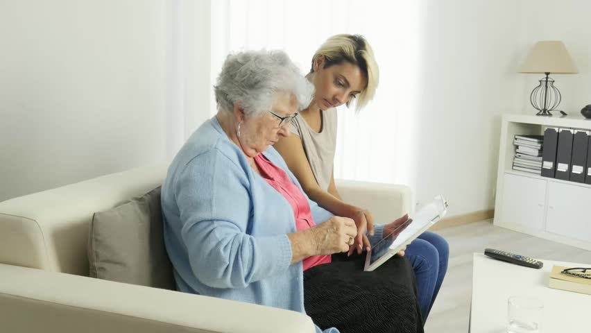Cheerful young woman  taking care of an elderly woman at home | Shutterstock HD Video #1024667759