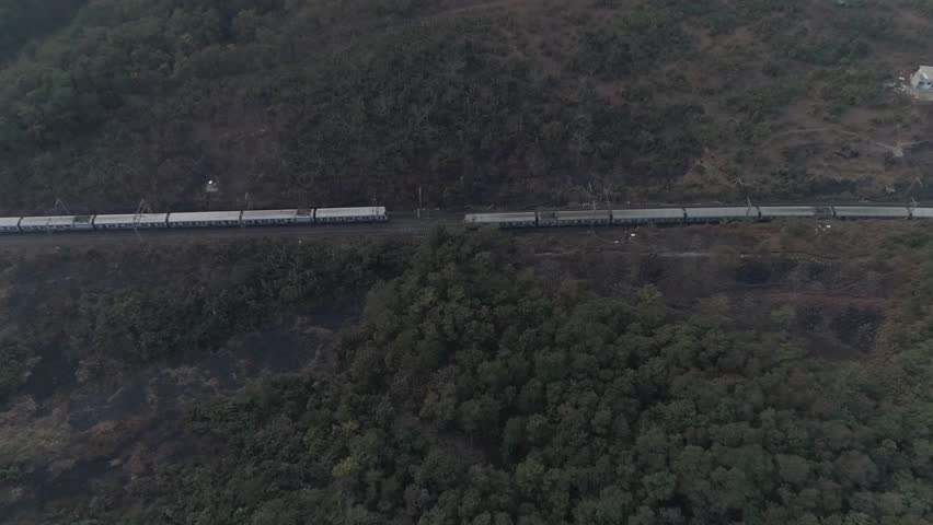 Aerial view of two Indian railways crossing each other surrounded by a dense jungle somewhere near the city of Mumbai.