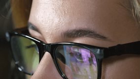 Extreme close up shot of young female office worker wearing glasses while having video conversation with colleagues at work