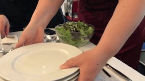 Woman puts the plates on the table. In the dining room, at the table with other people, video close-up