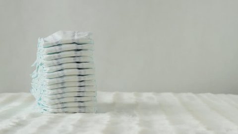 mother takes a stack of baby diapers on a white background, copy space, protection