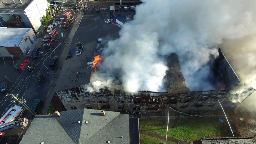 Aerial View of Firehoses Spraying Water onto the Charred Side of a Massive Condo as Thick Smoke Billows up in the Air from a Multi Alarm Fire