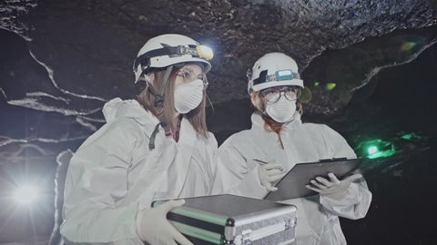 Two women scientists in bio-hazard suits testing