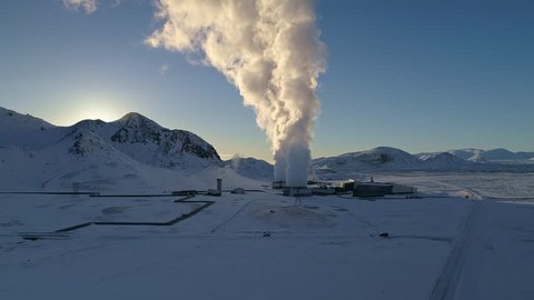 Aerial footage of a icelandic renewable power plant with steam rising up from the turbines, shot on a sunny day in winter, creating fantastic contrast of hot and cold