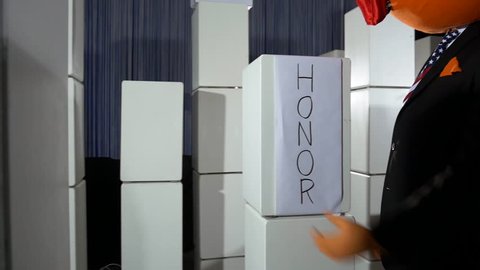 Parody of giant head president ripping down an honor label. Side view.
