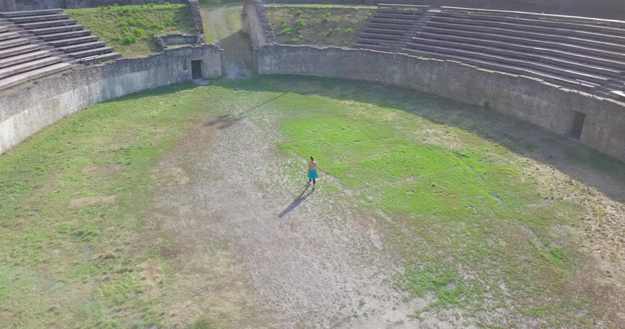 Girl Doing Series of Cartwheels and Walking in The Roman Amphitheater of Martigny, Valais - Aerial Orbiting Shot