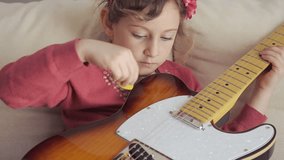 beautiful little girl plays electric guitar at home