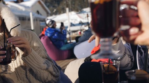 The cheerful company of friends at a ski resort in a restaurant rest and drink mulled wine glasses.