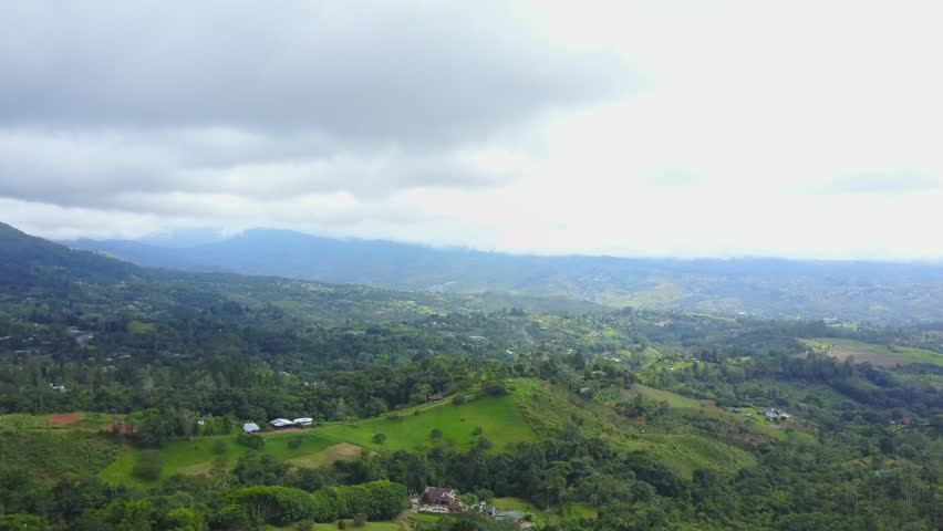 AERIAL: slowly moving over the mountainous terrain of Cali, Colombia that is being farmed on.