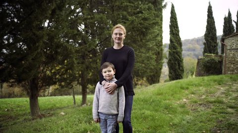 Portrait of a mother with her son standing in a field with trees in rural Tuscany, Italy. Wide to close up shot on 8k helium RED camera.