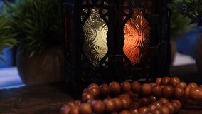 Ramadhan colored glass candle lamp on wooden table. Selective focus. Tilt up shot.