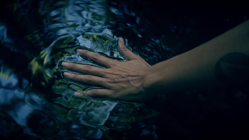 Female hand gliding on the top of smooth rippled water surface in dark mysterious black pond. Dragging healing motion with almost religious sentiment.  Royalty-Free Stock Footage #1024718579