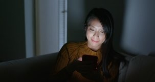 Woman use of cellphone and sit on sofa at night