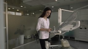 Good-looking young female dentist wearing white medical scrubs is examining a dental instruments. Doctor is checking them and putting the unnecessary one on a table. - Powered by Shutterstock - Get 15% off with code: PIKWIZARD15